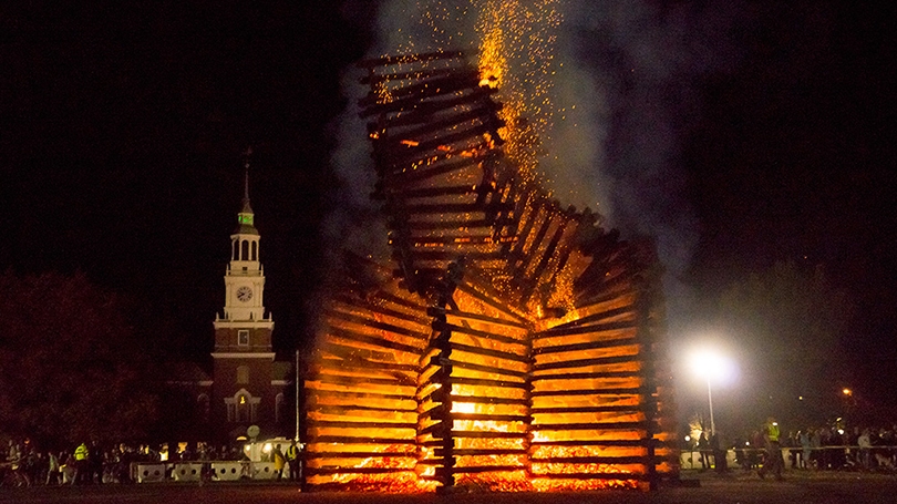 a bonfire burning with Baker Tower in the background