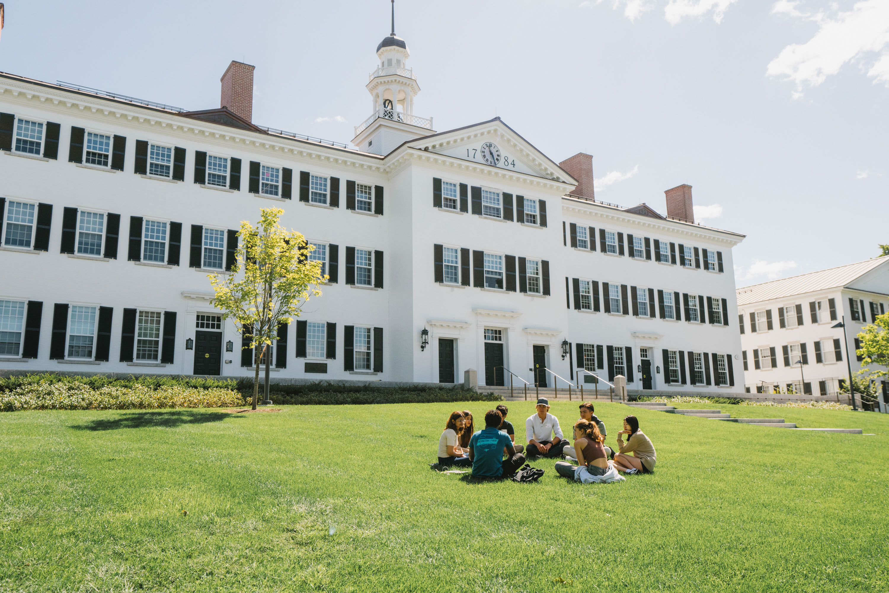 A group sits in a circle in front of Dartmouth Hall
