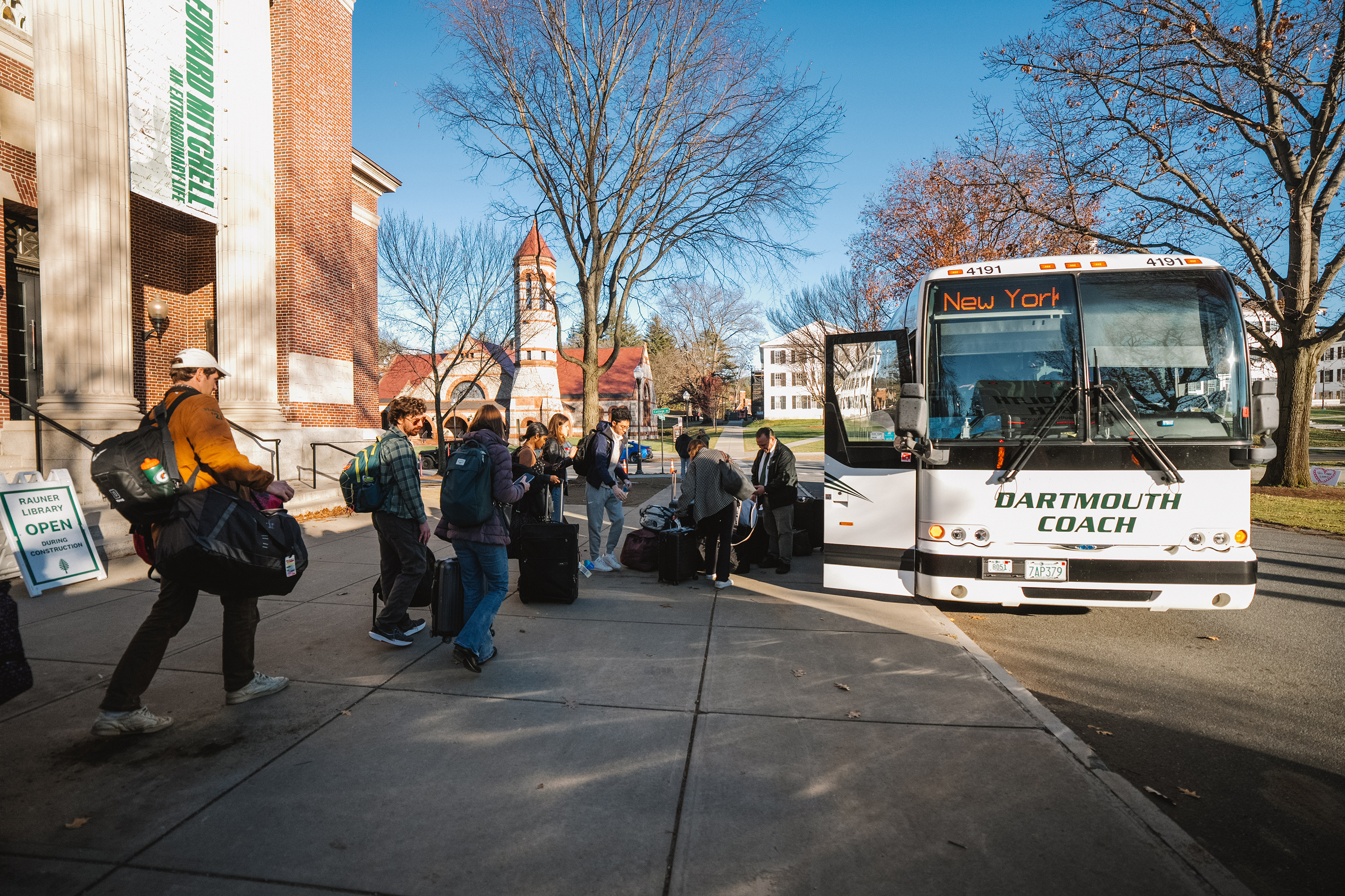 Students with large bags line up to board a bus
