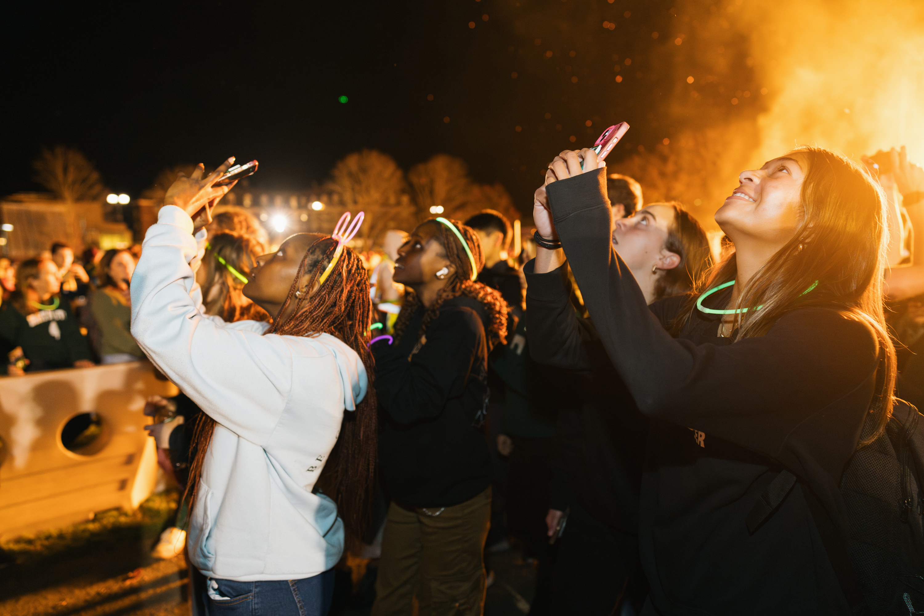 Students take photographs at the homecoming bonfire