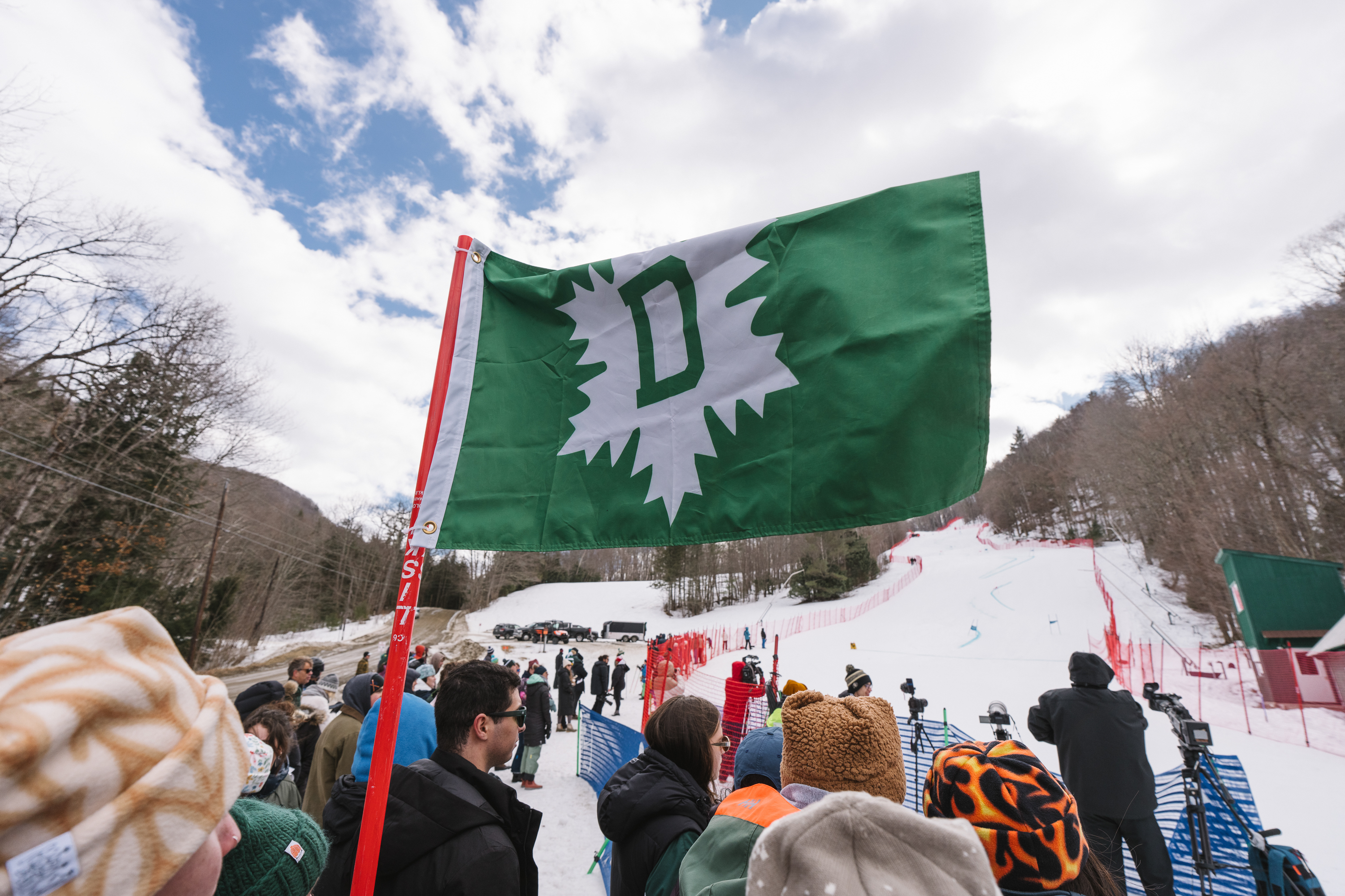 A large crowd of fans bunched up under a Dartmouth Skiway flag