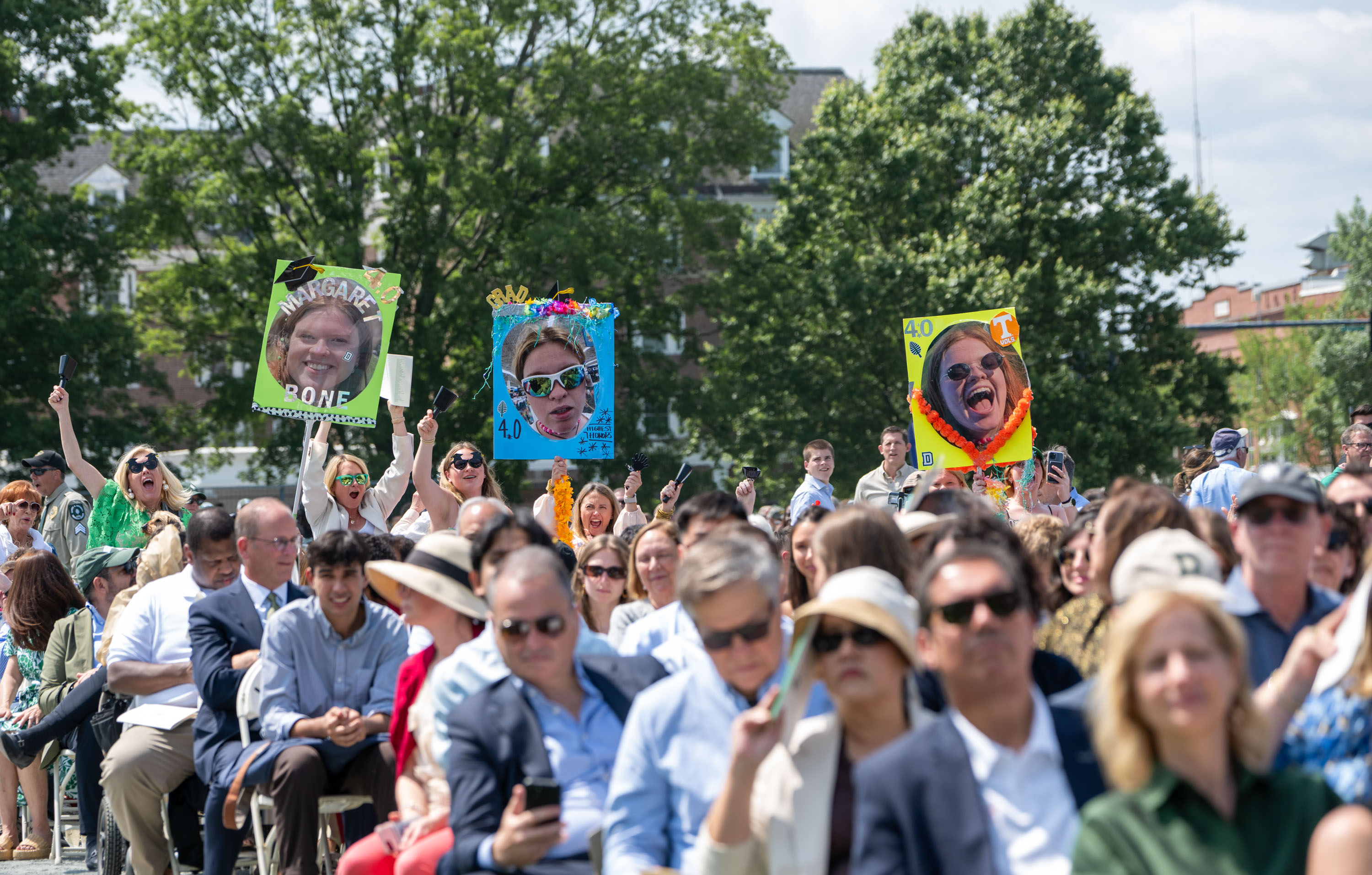 A family holds up 3 comedic signs for their graduate