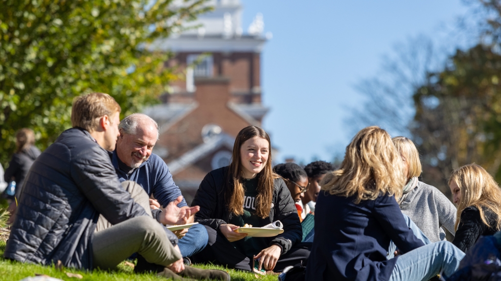 Students and families enjoy a picnic on the green grass at Dartmouth