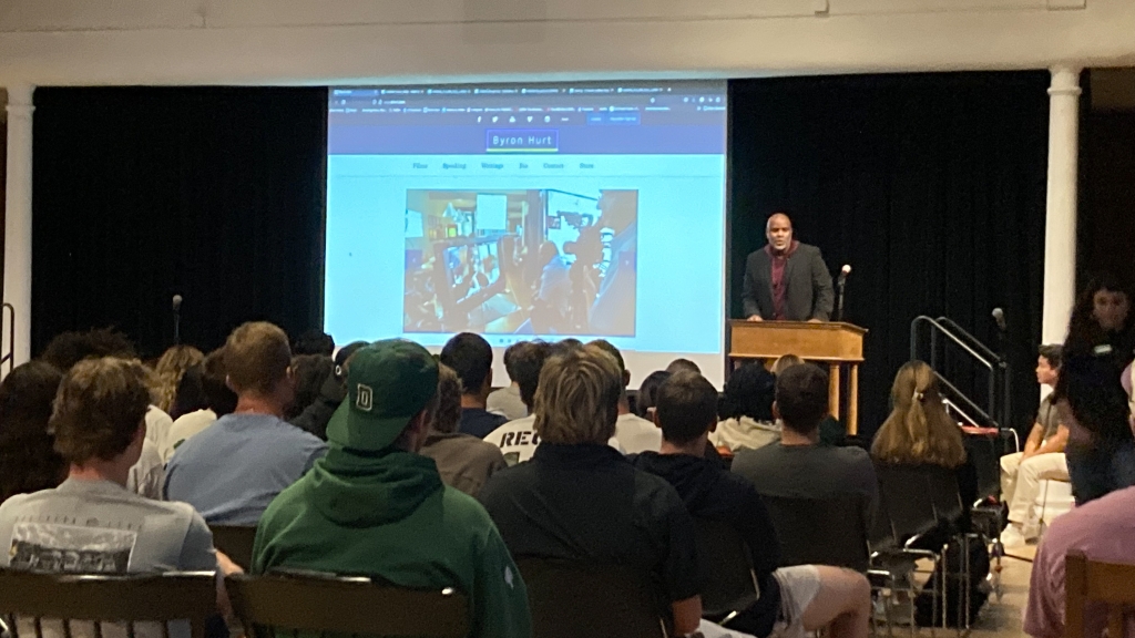 Byron Hurt standing in front of a projector speaking